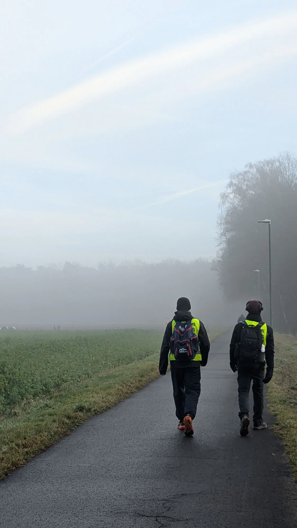 Bram en Tuur in fluohesjes op een mistige winterse weg tijdens de Warme Kerstmars