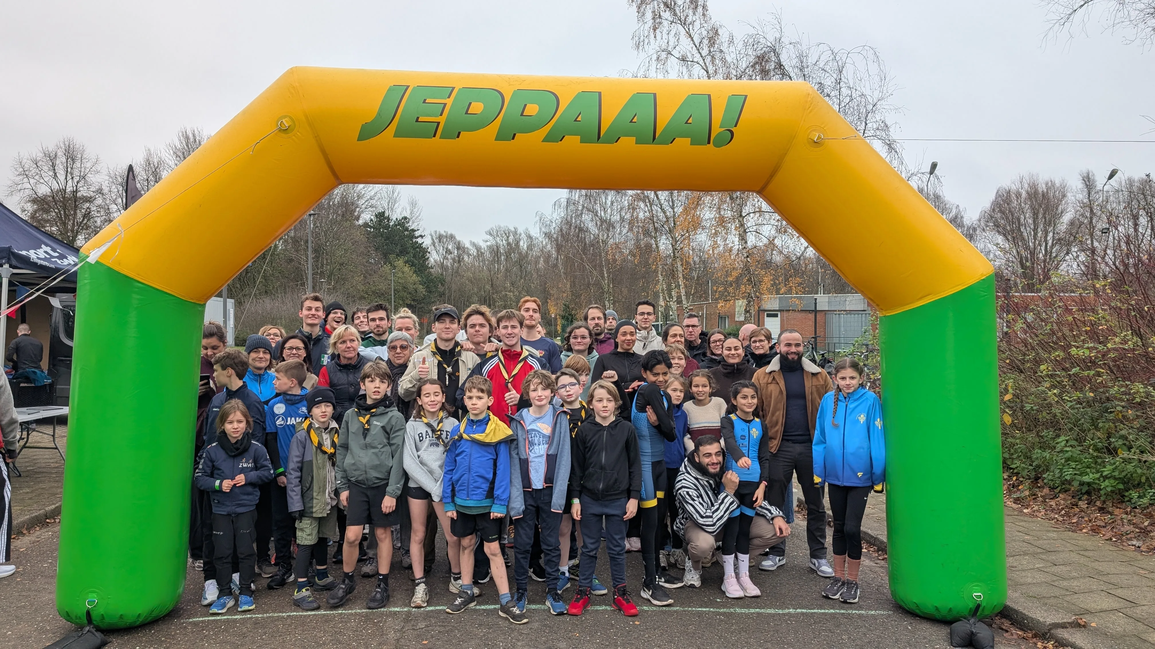 Groepsfoto van meer dan 100 deelnemers onder de JEPPAAA! finishboog